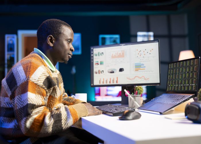 African american analyst checks financial balance and works on accounting analysis, exploring paths to grow enterprise income at home. Male advisor doing remote work using economy statistics.